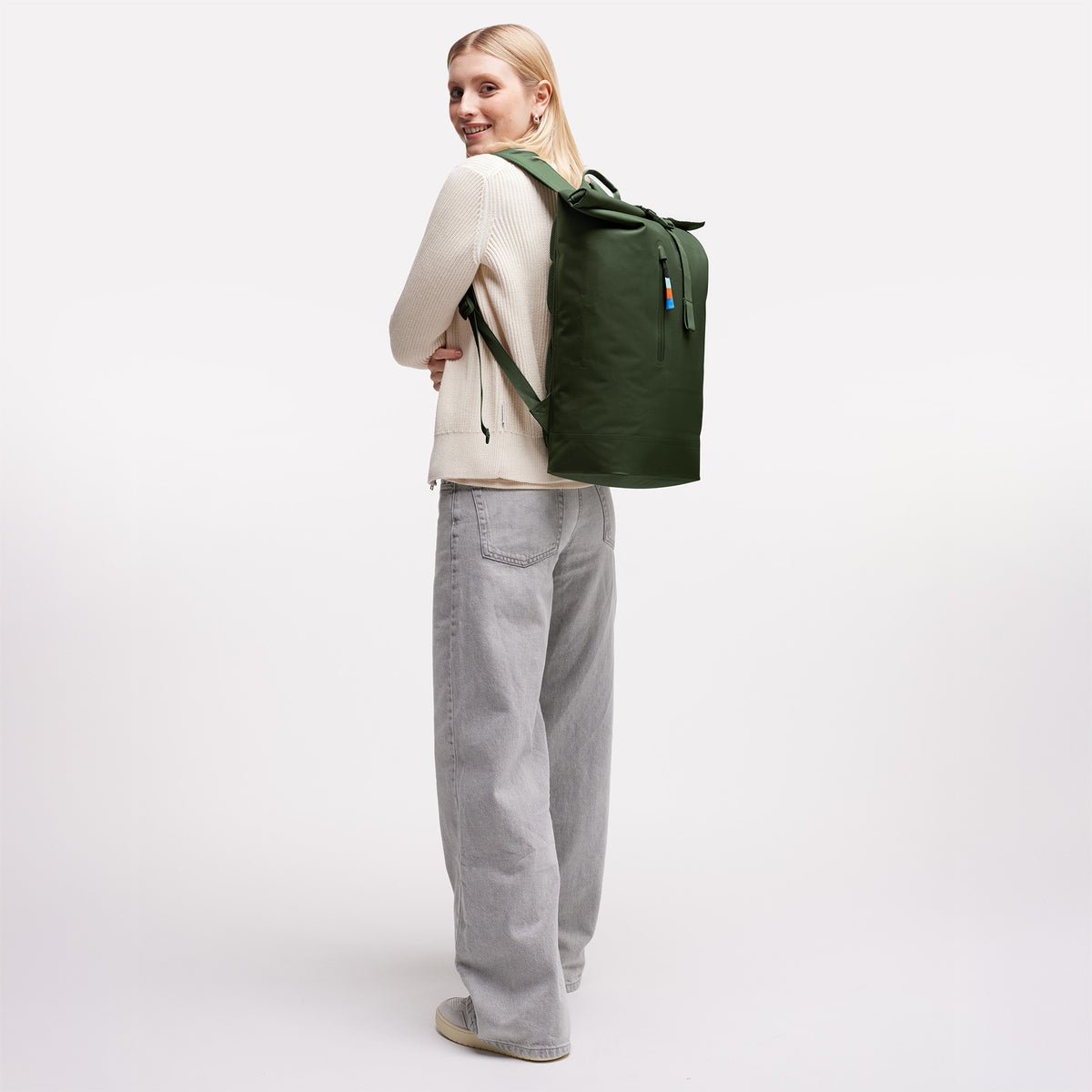 ROLLTOP LITE Rucksack in seafloor (tiefes Dunkelgrün) von einer Frau als Rucksack auf dem Rücken getragen.