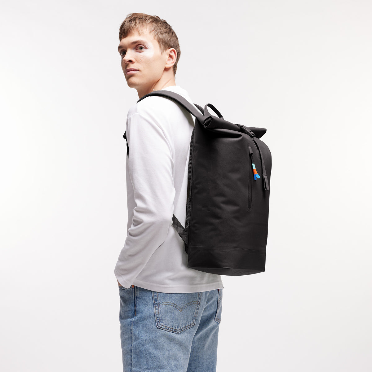 ROLLTOP LITE Rucksack in mussel (dunkles Braun-Grau) von einem Mann auf dem Rücken getragen.