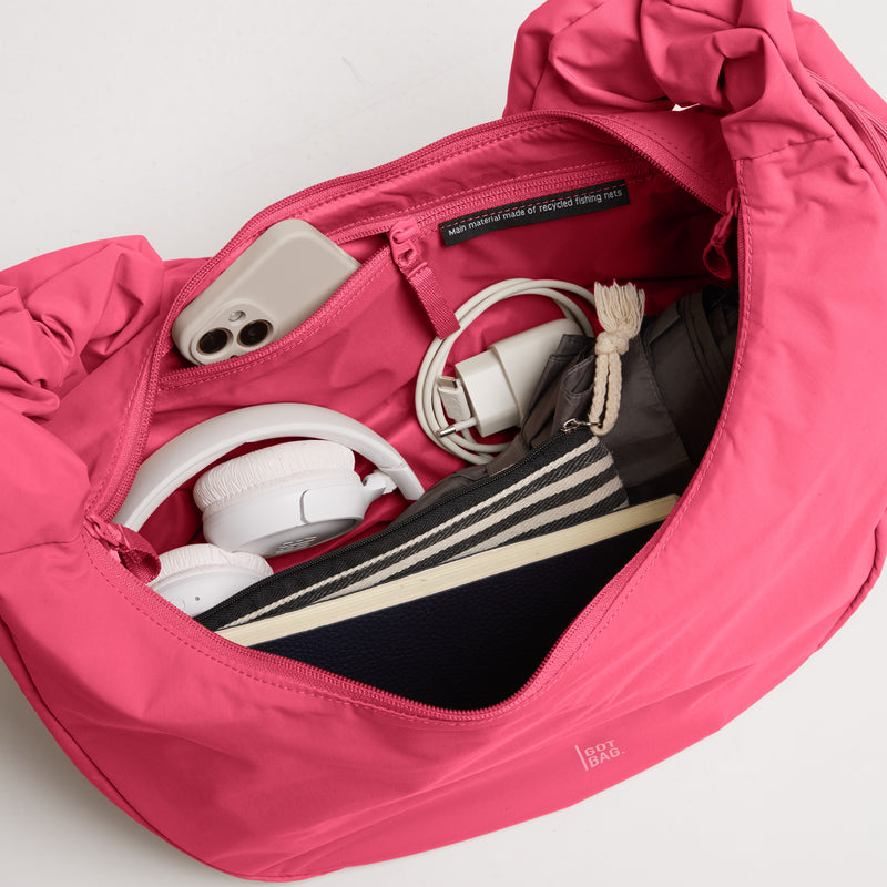 MOON BAG RUFFLE Tasche in salina pink (leuchtendes Pink), innen mit Handy, Kopfhörern & Etikett über Recyclingmaterial.