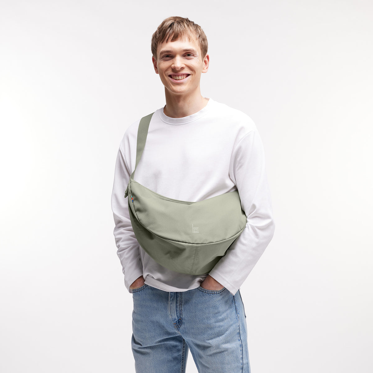 MOON BAG LARGE Tasche in seabed (helles Olivgrün) von einem Mann crossbody getragen.