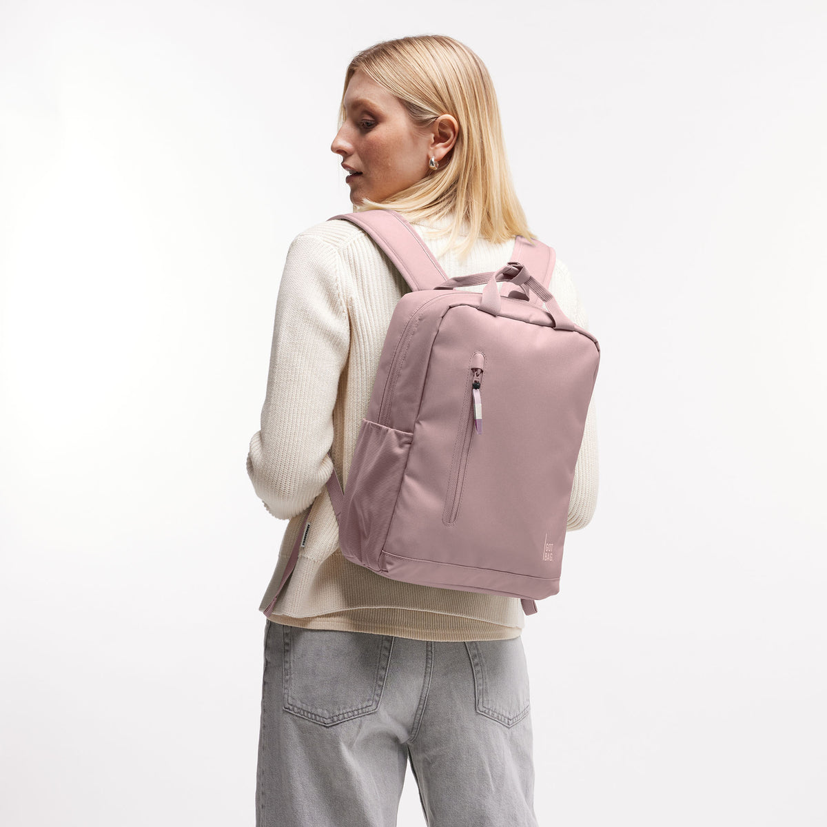 DAYPACK 2.0 MONOCHROME EDITION Rucksack in red sand (pastellfarbenes helles Rosa) von einer Frau als Rucksack auf dem Rücken getragen.
