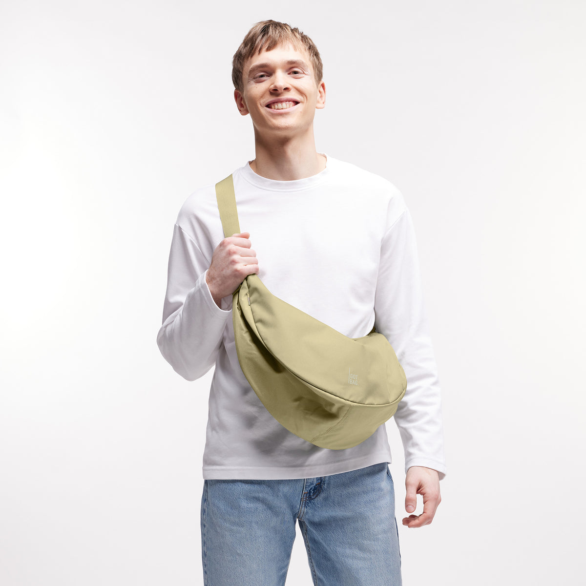 MOON BAG LARGE Tasche in nori (pastellfarbenes Pistaziengrün) von einem Mann über der Schulter getragen.