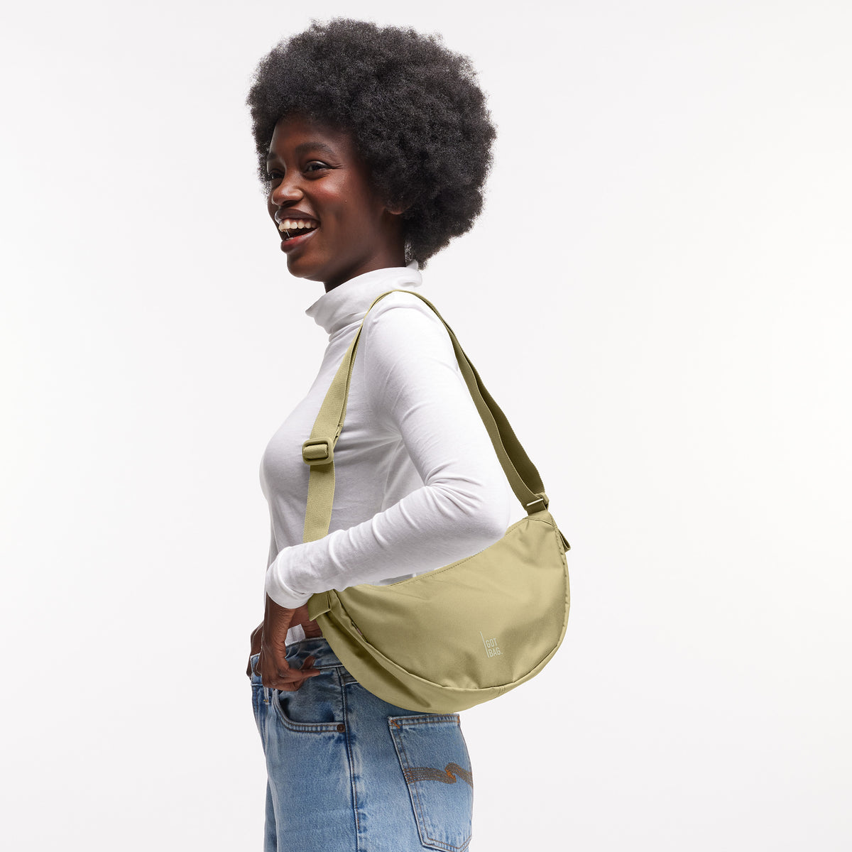 MOON BAG SMALL Tasche in nori (pastellfarbenes Pistaziengrün) von einer Frau crossbody getragen.