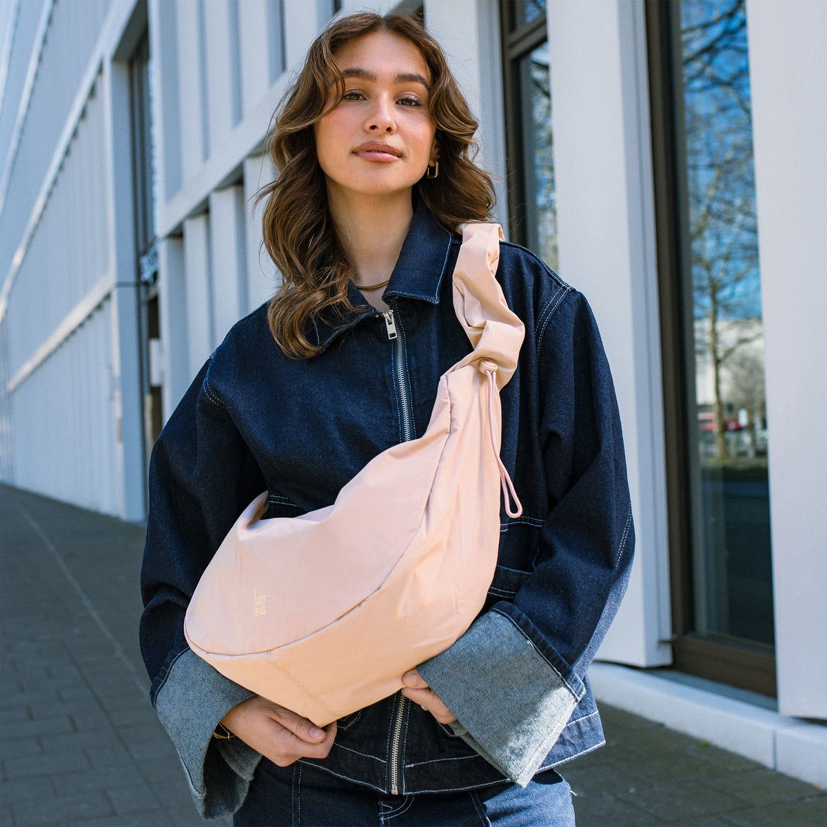 MOON BAG RUFFLE Tasche in pearl (helles Puder-Rosa) von einer Frau crossbody getragen.