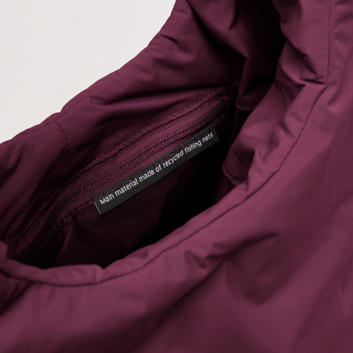 CLOUD SHOULDER BAG Tasche in kraken (Weinrot), Detailaufnahme des Innenbereichs mit Etikett Main material made of recycled fishing nets.