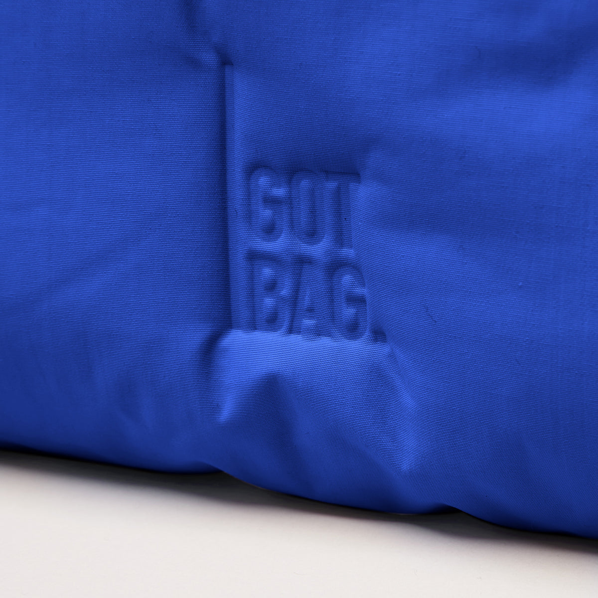 CLOUD SHOULDER Tasche in cobalt (leuchtendes Kobaltblau), Detailaufnahme des geprägten GUT BAG Logos.