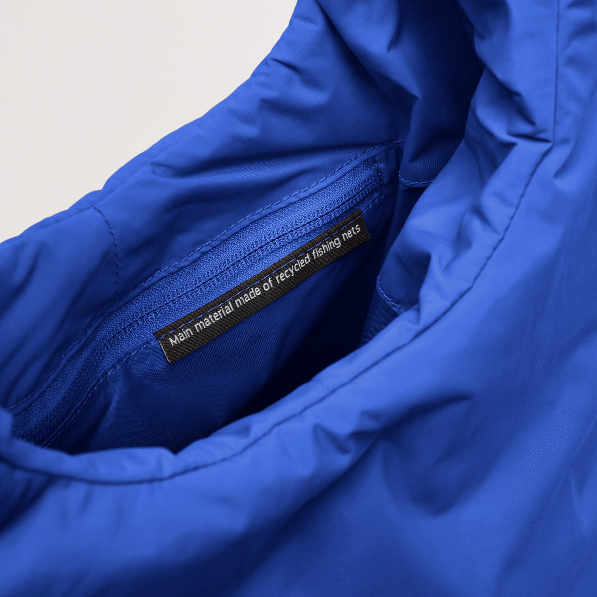 CLOUD SHOULDER Tasche in cobalt (leuchtendes Kobaltblau), Detailaufnahme des Innenfutters mit Label: Main material made of recycled fishing nets.