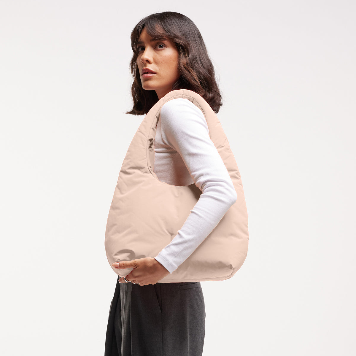 CLOUD SHOULDER Tasche in pearl (helles Puder-Rosa) von einer Frau über der Schulter getragen.