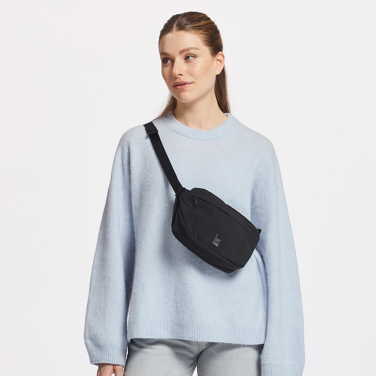 ADAPT SLING BAG Tasche in black (Schwarz) von einer Frau crossbody getragen.