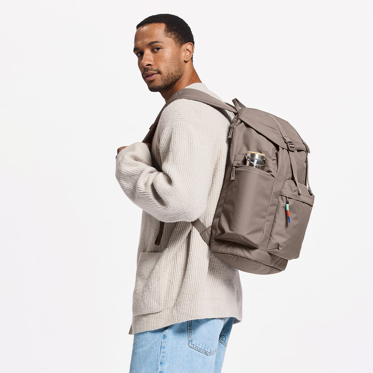 FLAP PACK LARGE Rucksack in oyster (klassisches Taupe-Braun) von einem Mann als Rucksack auf dem Rücken getragen.