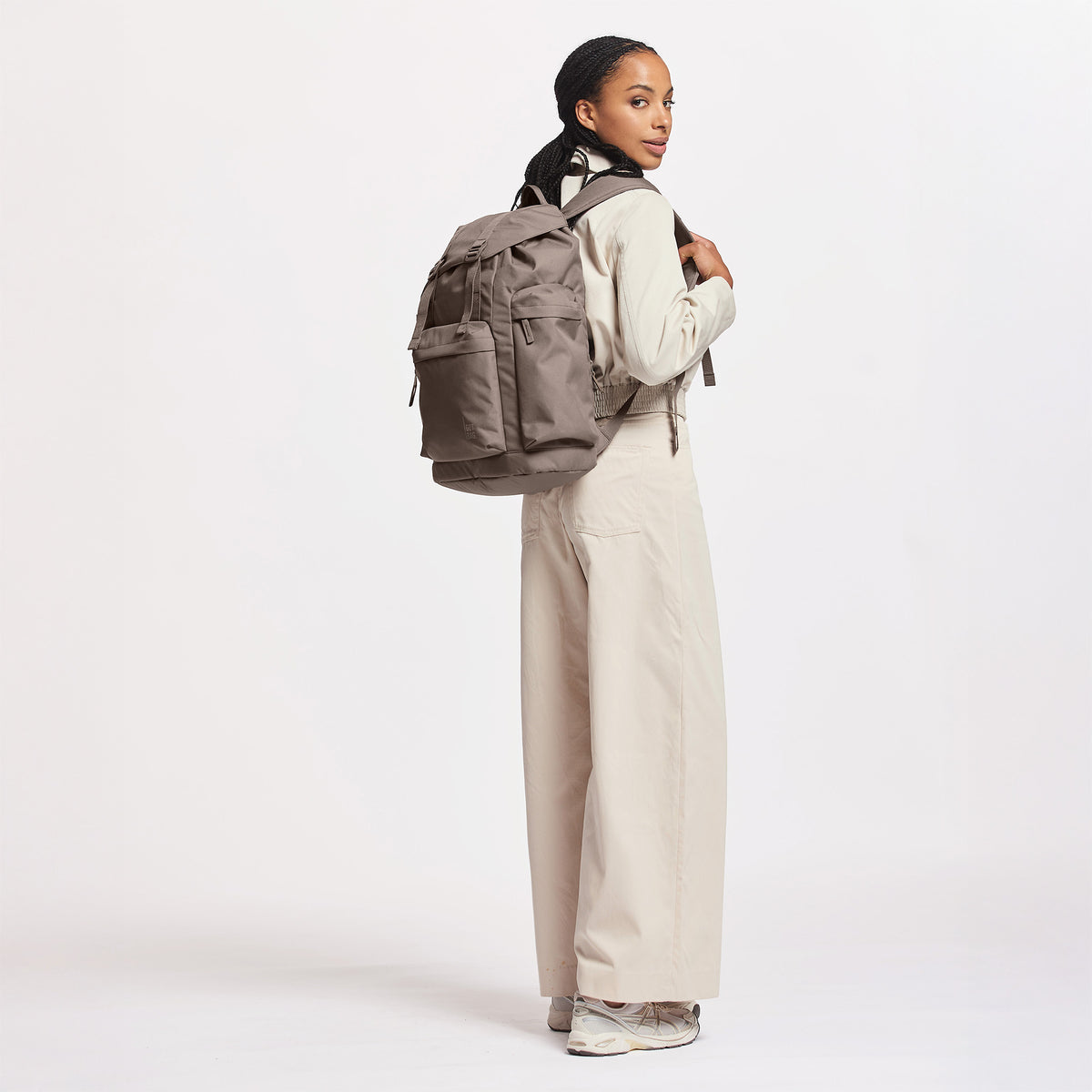 FLAP PACK LARGE Rucksack in oyster (klassisches Taupe-Braun) von einer Frau auf dem Rücken getragen.
