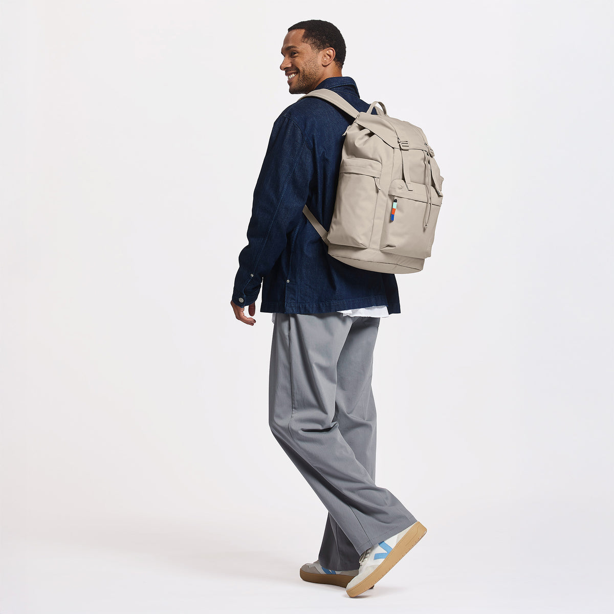 FLAP PACK LARGE Rucksack in scallop (helles Beige) von einem Mann als Rucksack auf dem Rücken getragen.