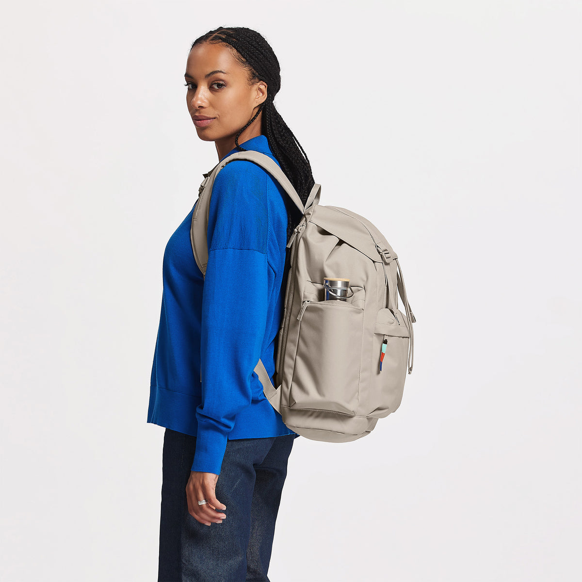 FLAP PACK LARGE Rucksack in scallop (helles Beige) von einer Frau auf dem Rücken getragen.