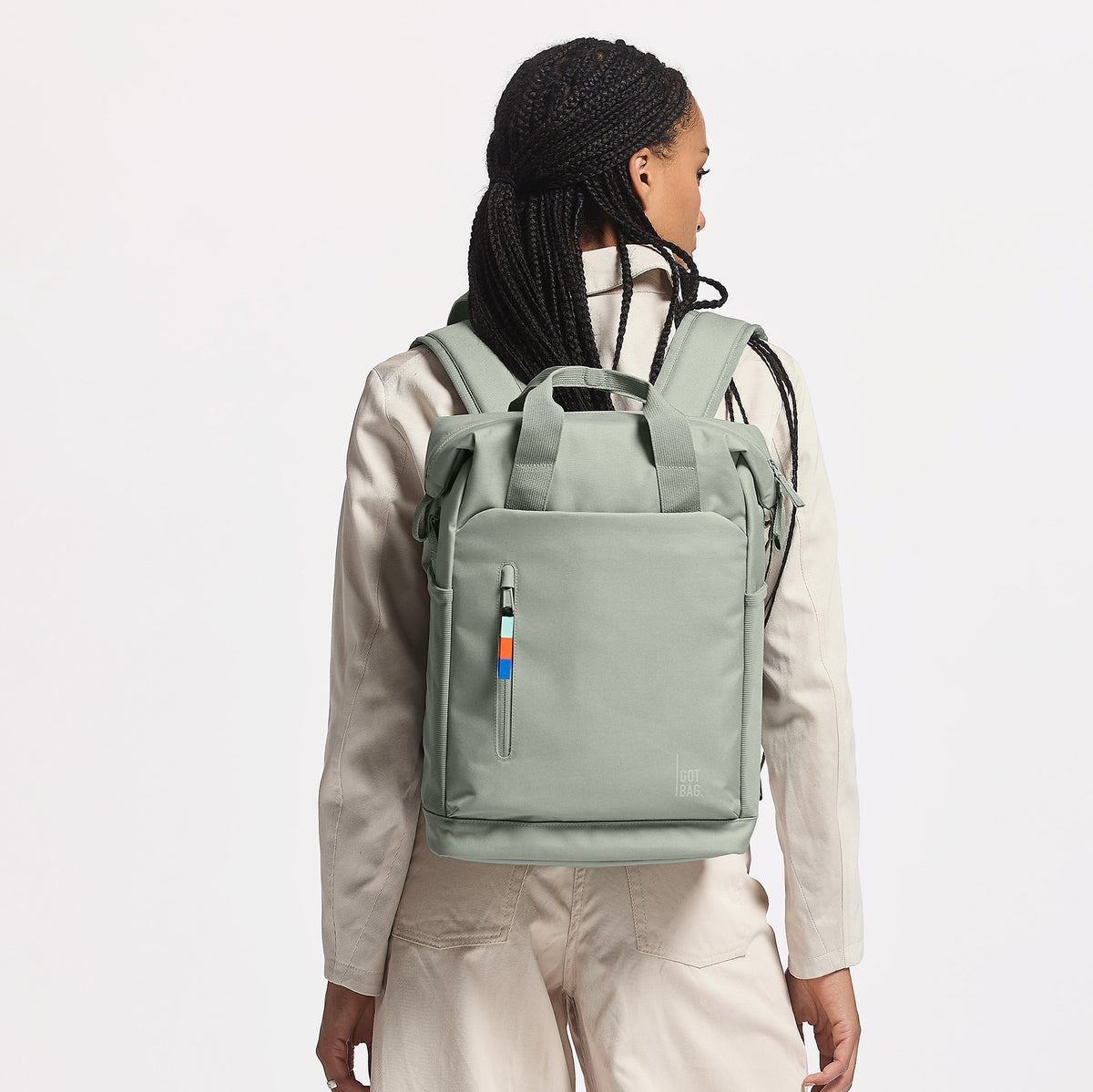 FLOW PACK Rucksack in bass (Salbeigrün) von einer Frau als Rucksack auf dem Rücken getragen.
