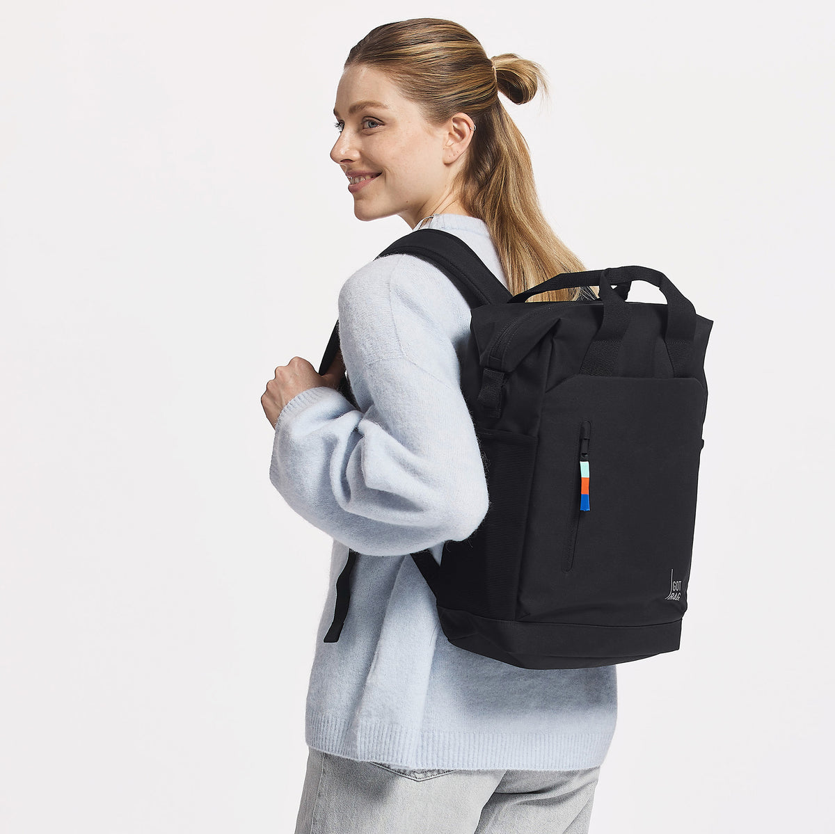 FLOW PACK Rucksack in black (Schwarz) von einer Frau als Rucksack auf dem Rücken getragen.