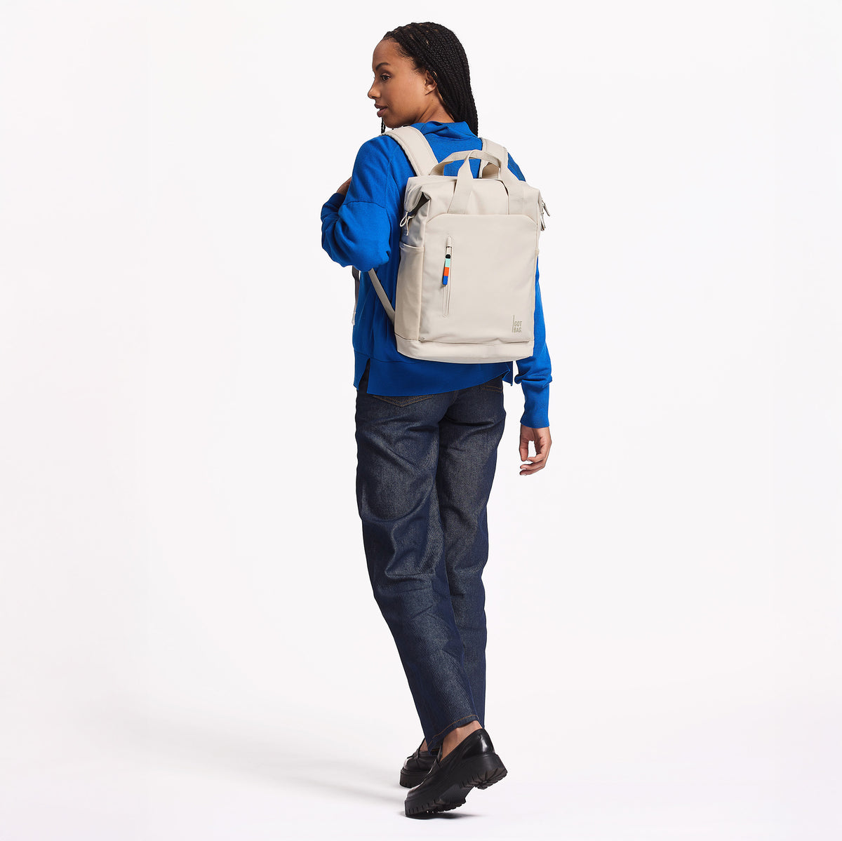 FLOW PACK Rucksack in soft shell (warmes Cremeweiß) von einer Frau auf dem Rücken getragen.