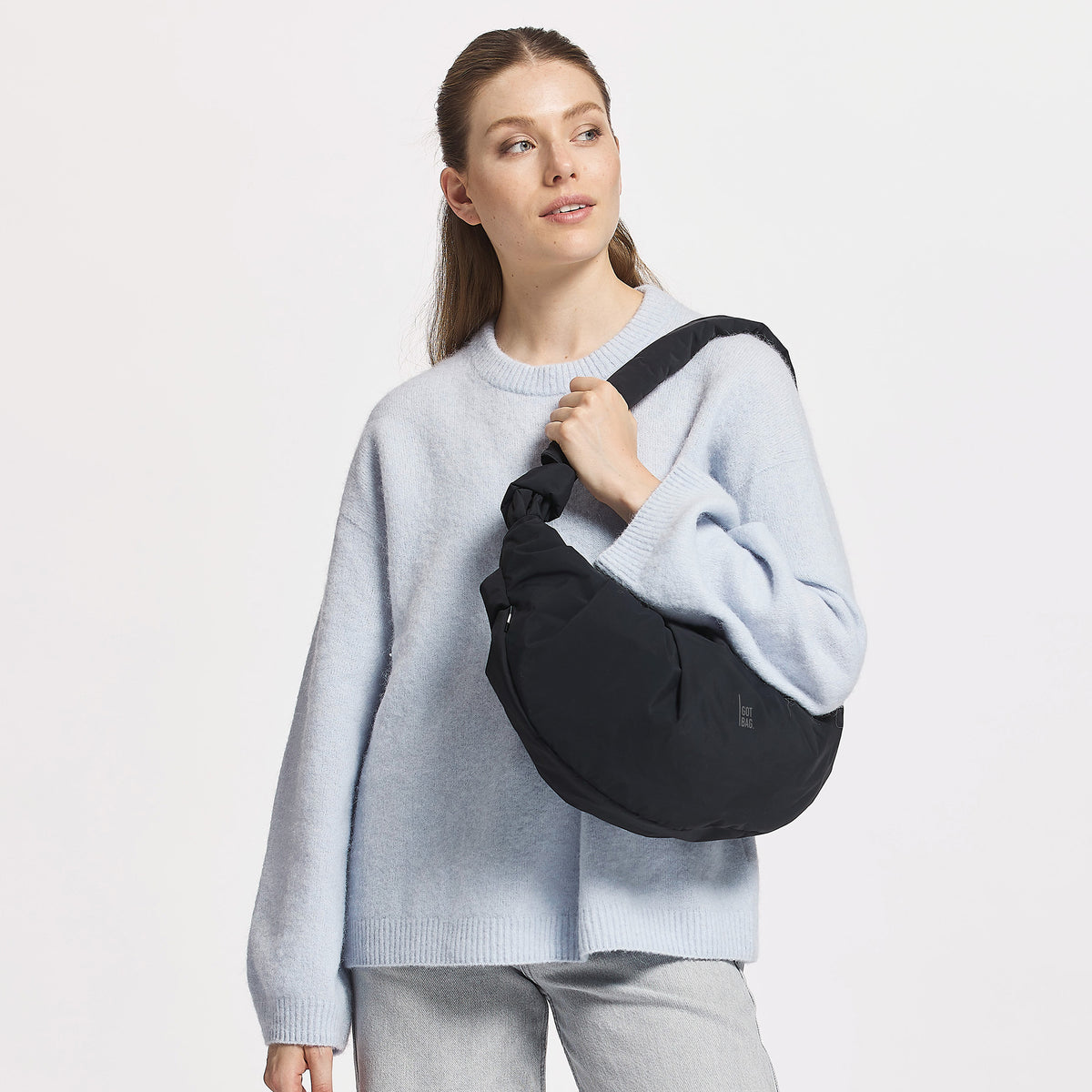 PLEAT MOON BAG LARGE Tasche in black (Schwarz) von einer Frau crossbody getragen.