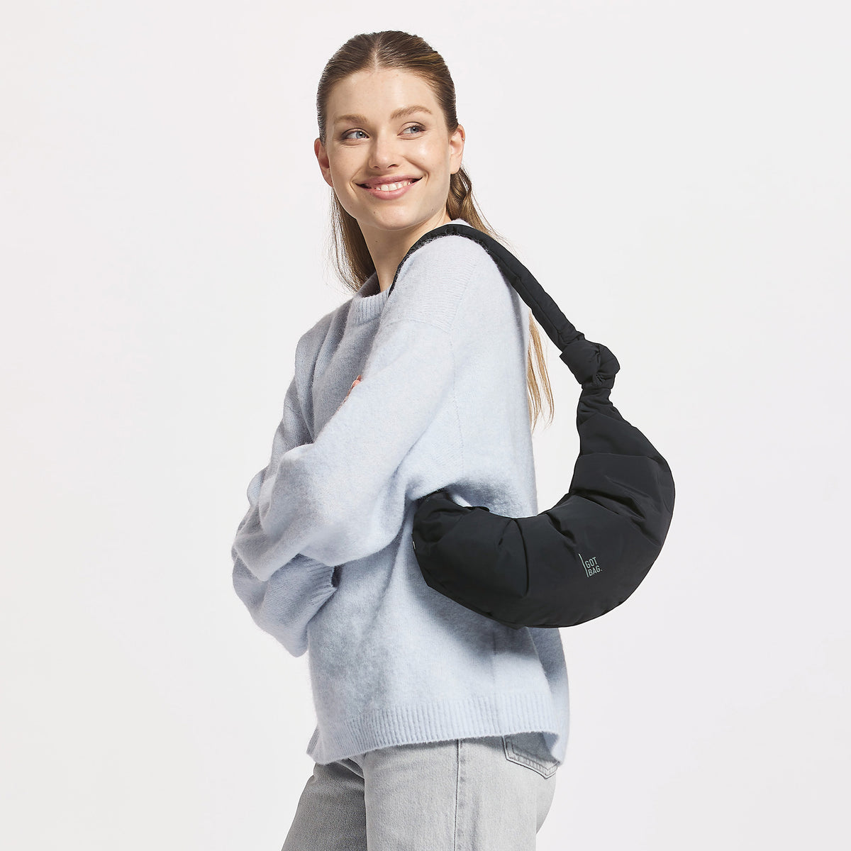 PLEAT MOON BAG SMALL Tasche in black (Schwarz) von einer Frau über der Schulter getragen.