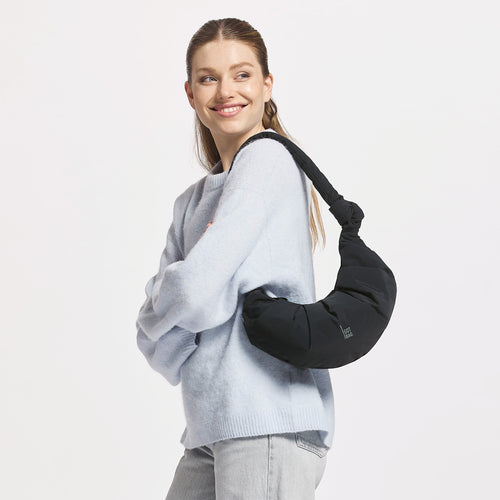 PLEAT MOON BAG SMALL Tasche in black (Schwarz) von einer Frau über der Schulter getragen.