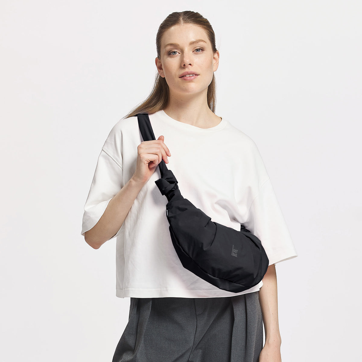 PLEAT MOON BAG SMALL Tasche in black (Schwarz) von einer Frau crossbody getragen.