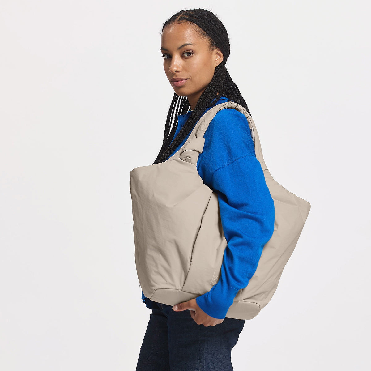 PLEAT TOTE BAG Tasche in scallop (helles Beige) von einer Frau über der Schulter getragen.