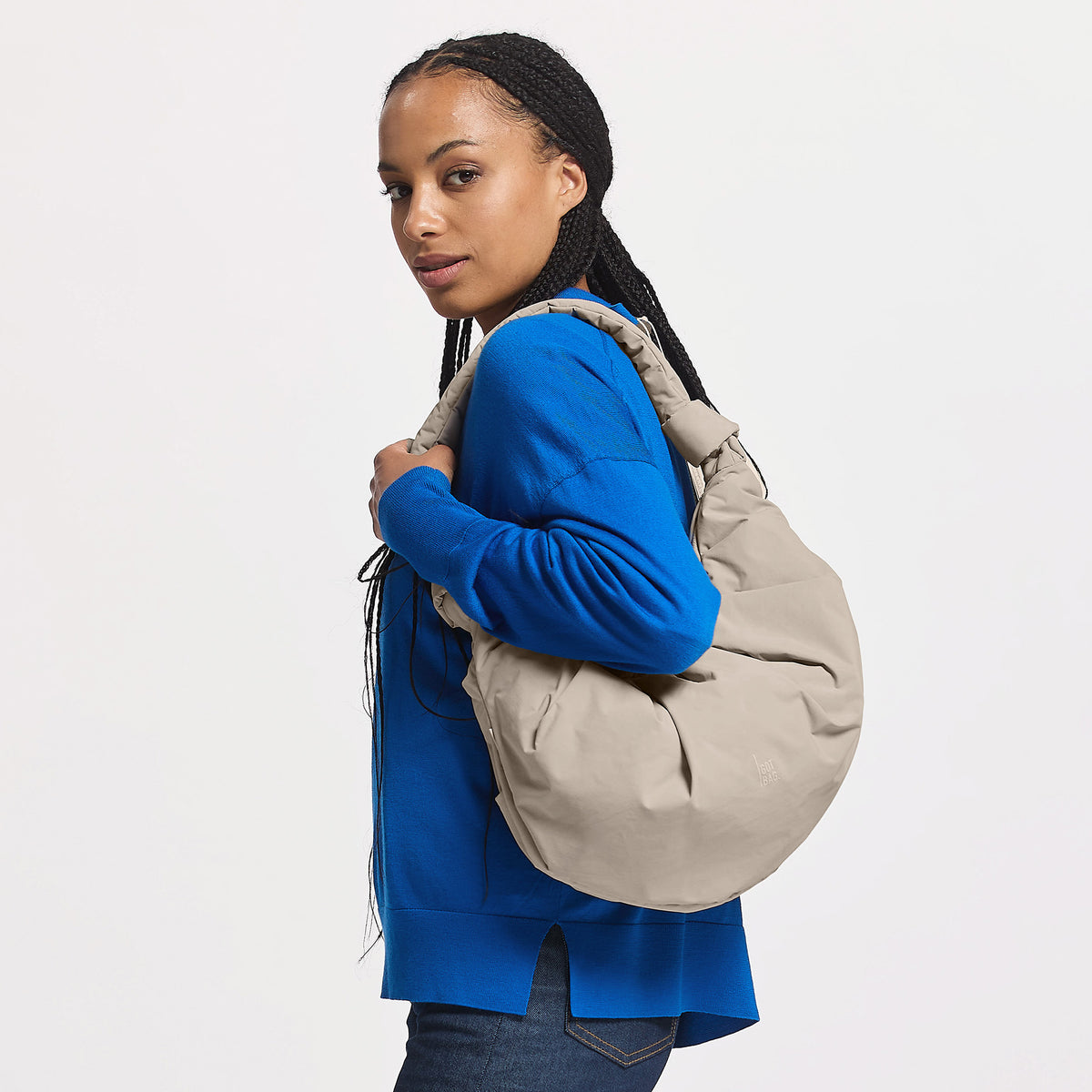 PLEAT TOTE MOON BAG LARGE Tasche in scallop (helles Beige) von einer Frau über der Schulter getragen.