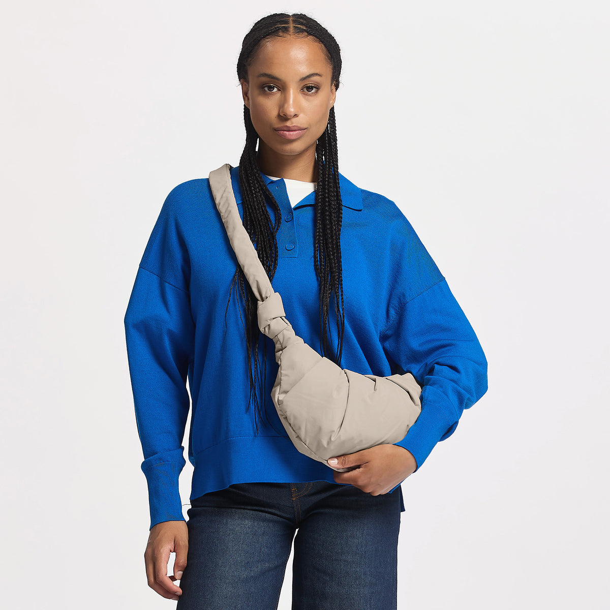 PLEAT TOTE MOON BAG SMALL Tasche in scallop (helles Beige) von einer Frau crossbody getragen und in der Hand gehalten.