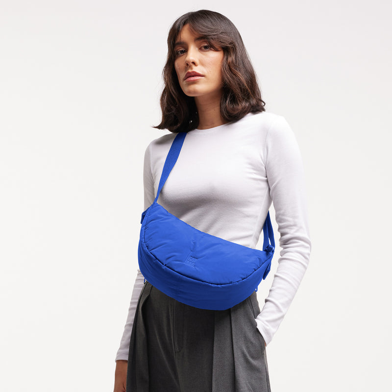 CLOUD MOON BAG SMALL Tasche in cobalt (leuchtendes Kobaltblau) von einer Frau crossbody getragen.