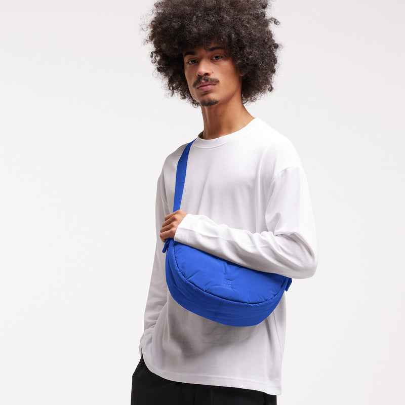 CLOUD MOON BAG SMALL Tasche in cobalt (leuchtendes Kobaltblau) von einem Mann crossbody getragen.