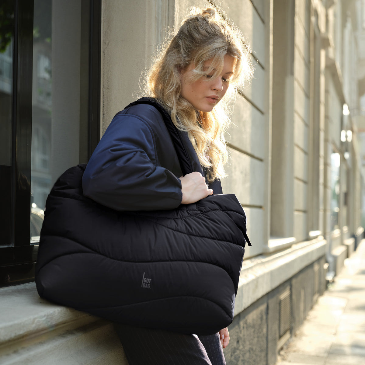 WAVY PUFFER EVERYDAY BAG Tasche in black (Schwarz) von einer Frau getragen.