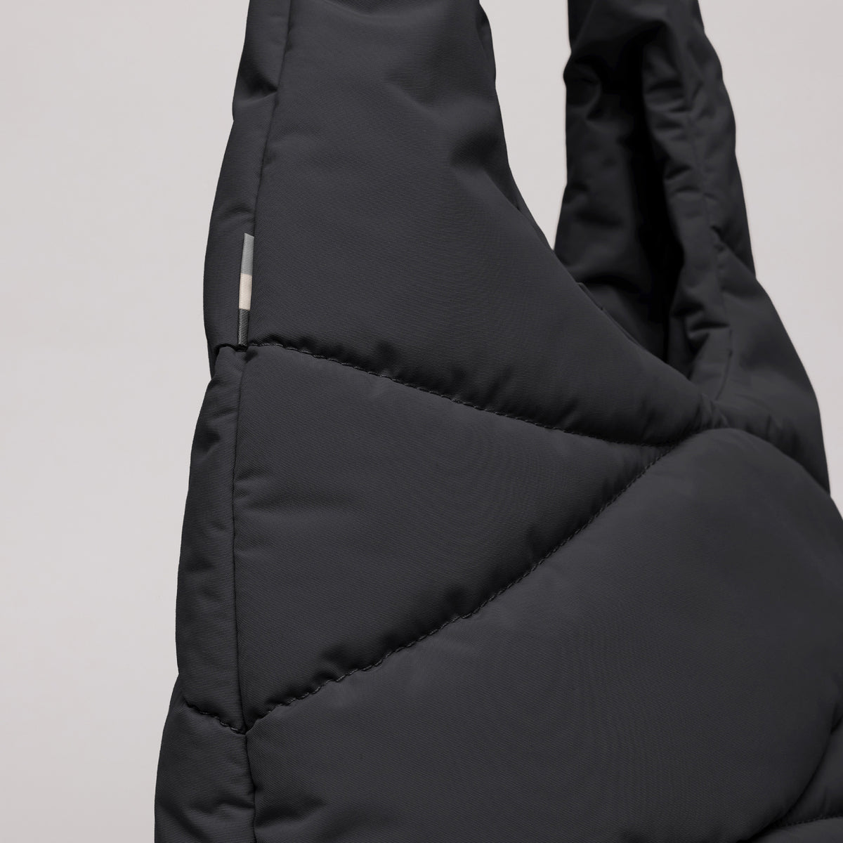 WAVY PUFFER SHOULDER BAG Tasche in black (Schwarz) mit gesteppter Textur als Detailaufnahme.