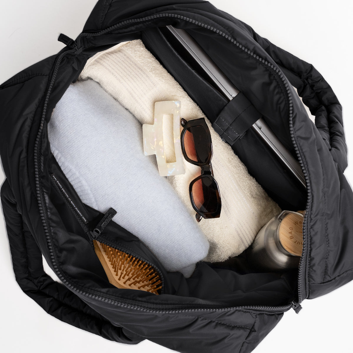 WAVY PUFFER EVERYDAY BAG Tasche in black (Schwarz) als Detailaufnahme, geöffnet mit Inhalt.