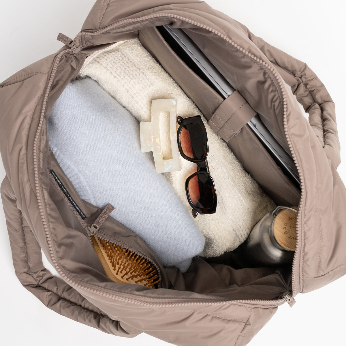 WAVY PUFFER EVERYDAY BAG Tasche in oyster (klassisches Taupe-Braun), geöffnet mit Pullovern, Laptop und Trinkflasche.