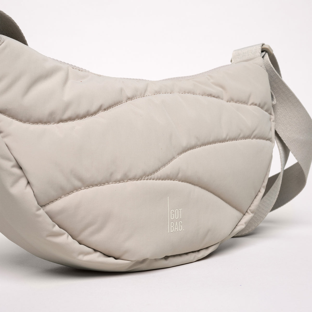 WAVY PUFFER MOON BAG Tasche in scallop (helles Beige) mit wellenförmiger Steppung.
