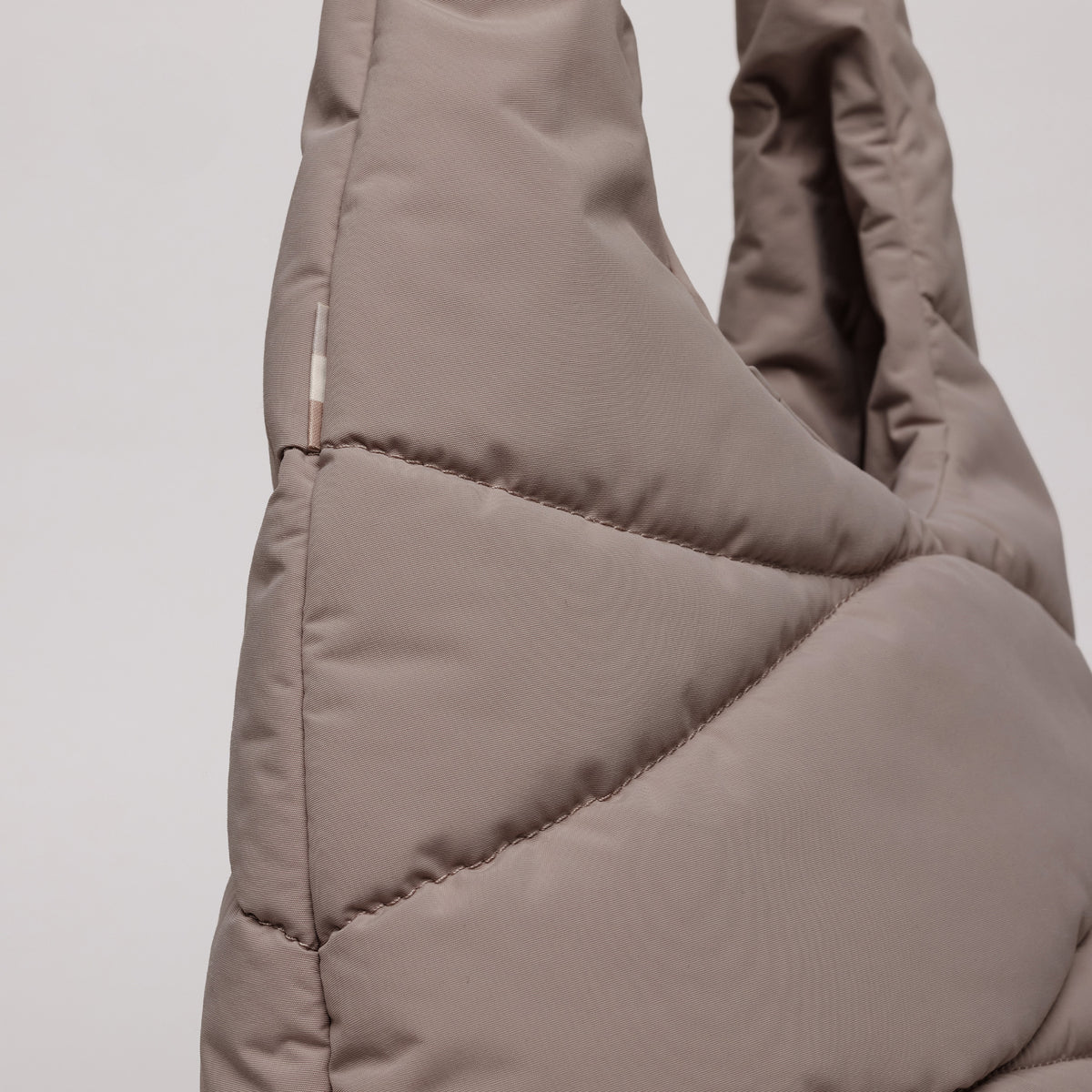 WAVY PUFFER SHOULDER BAG Tasche in oyster (klassisches Taupe-Braun) als Detailaufnahme.
