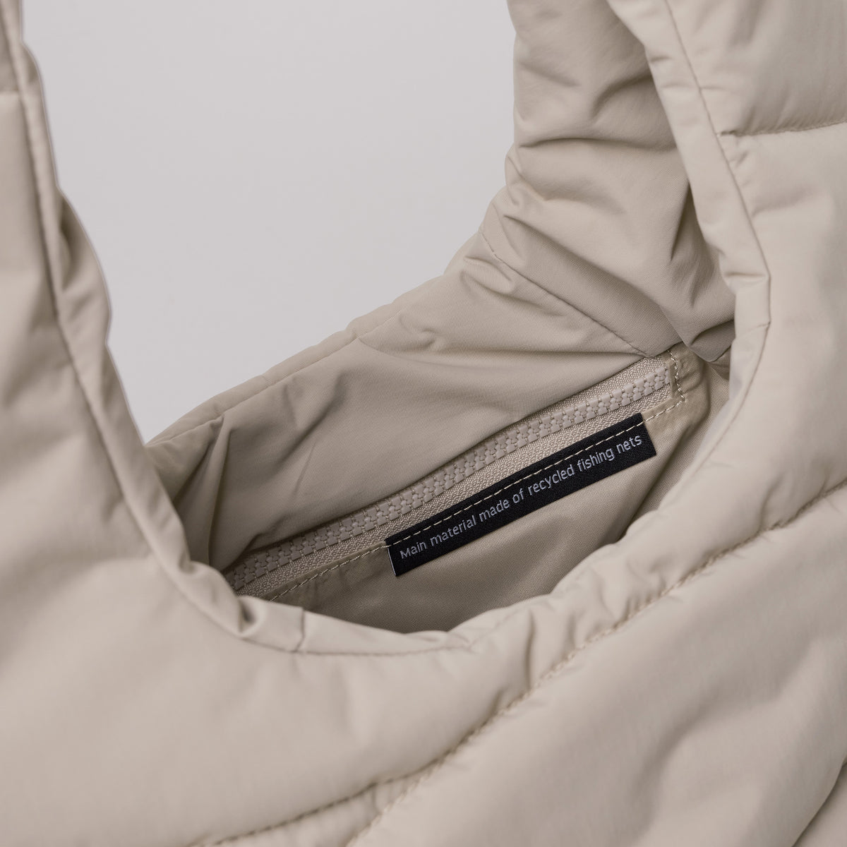 WAVY PUFFER SHOULDER BAG Tasche in scallop (helles Beige) als Detailaufnahme des Innenraums mit Reißverschluss.
