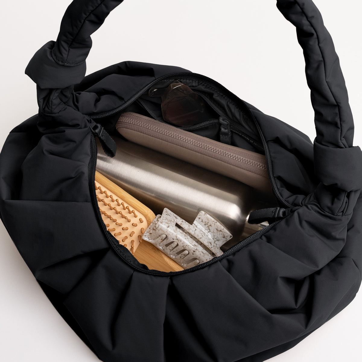 PLEAT MOON BAG LARGE Tasche in black (Schwarz) als Innenansicht mit Inhalt.