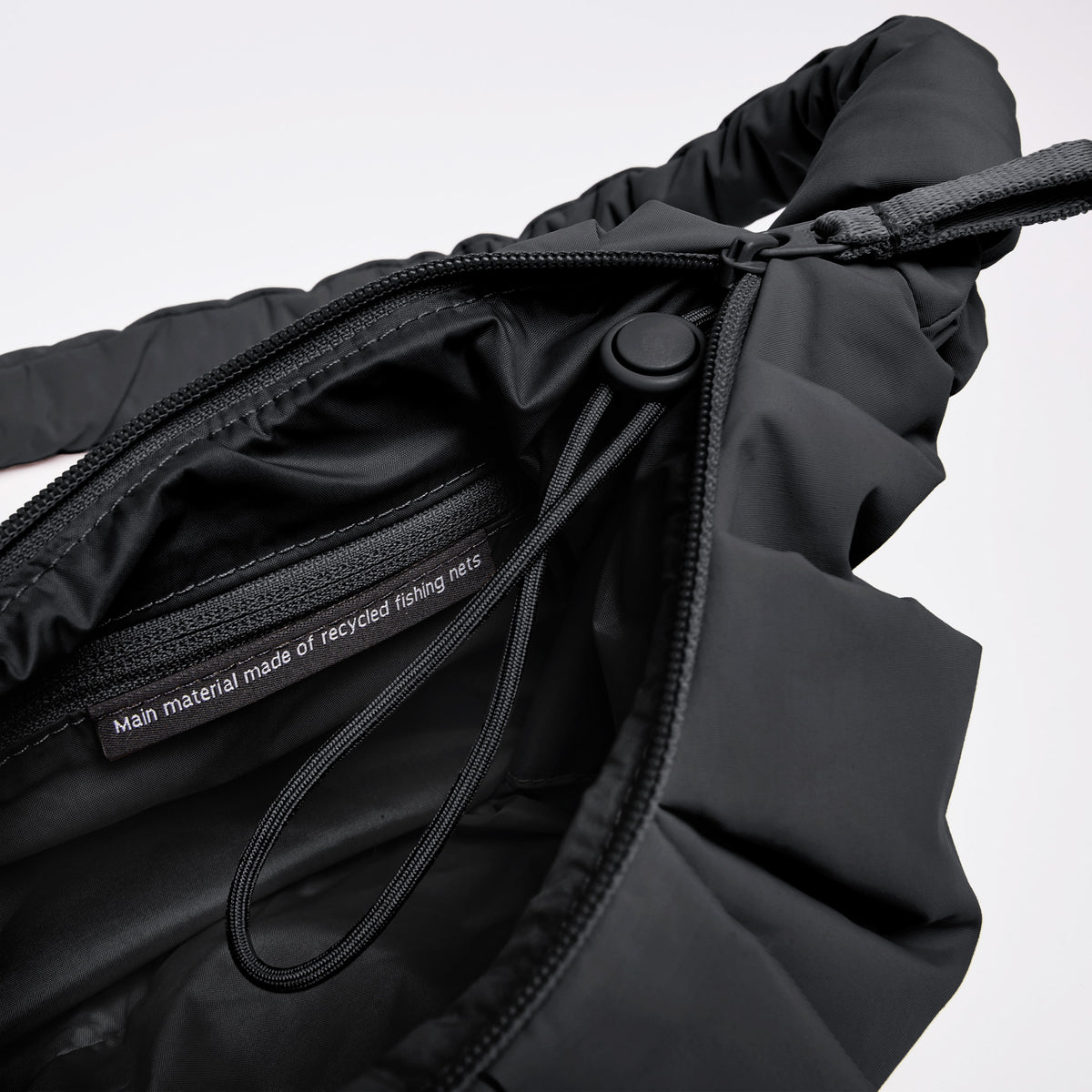 PLEAT MOON BAG SMALL Tasche in black (Schwarz) Innenansicht mit Labelaufschrift Main material made of recycled fishing nets.
