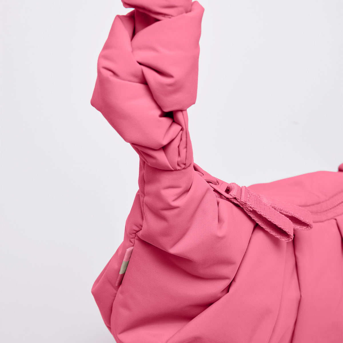 PLEAT MOON BAG SMALL Tasche in salina pink (leuchtendes Pink) als Detailaufnahme der geknoteten Tasche.