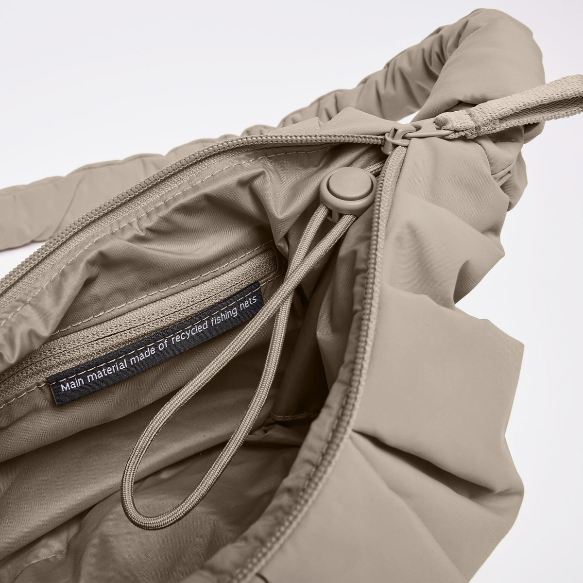 PLEAT MOON BAG SMALL Tasche in sallop, Detailaufnahme mit Innenetikett: Hauptmaterial aus recycelten Fischernetzen.