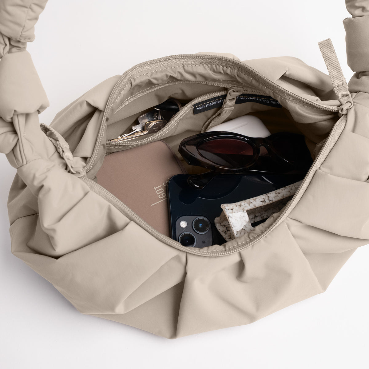 PLEAT MOON BAG SMALL Tasche in sallop, geöffnet mit Gegenständen innen.
