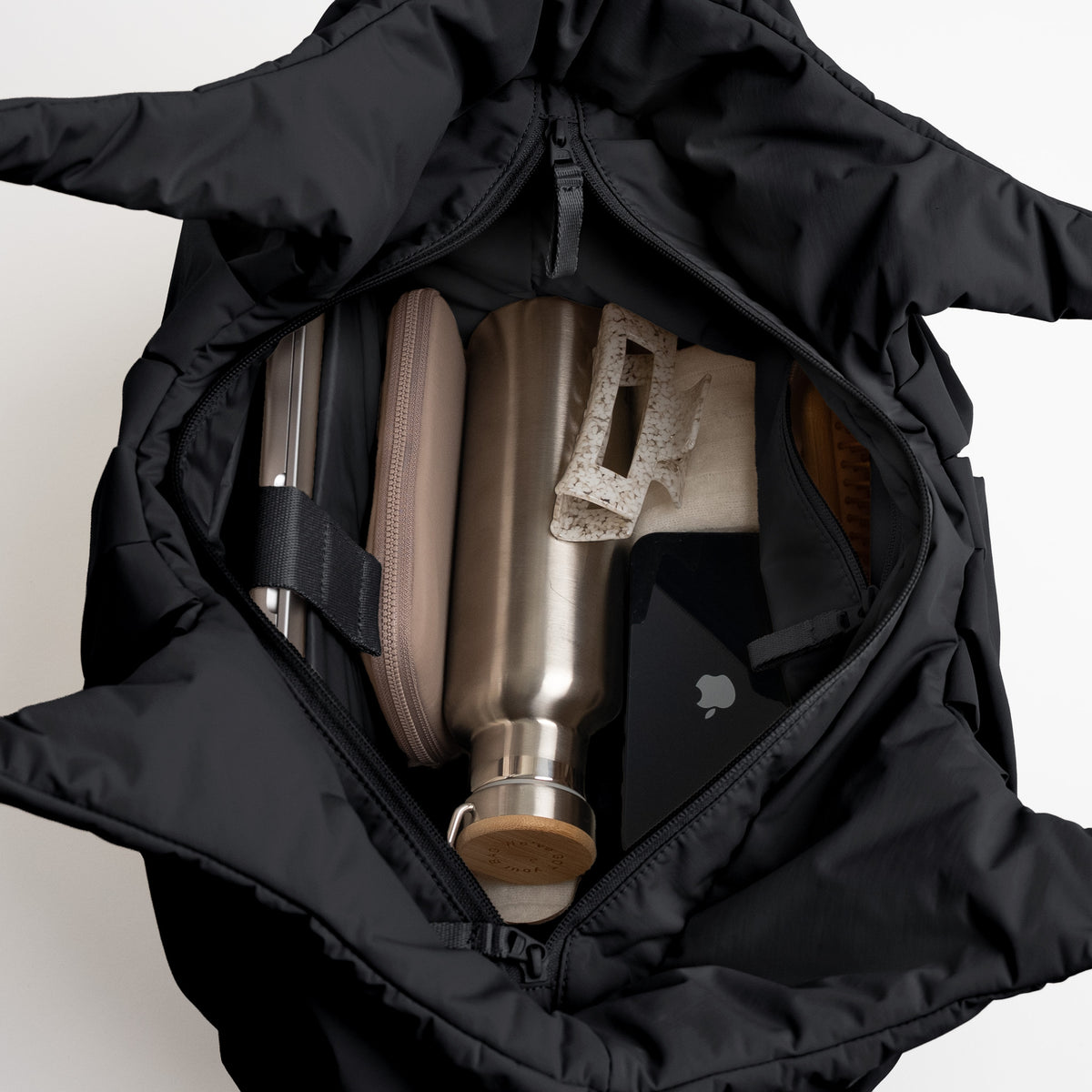 PLEAT TOTE BAG Tasche in black (Schwarz) von oben mit Inhalt wie Trinkflasche, Etui und Smartphone.