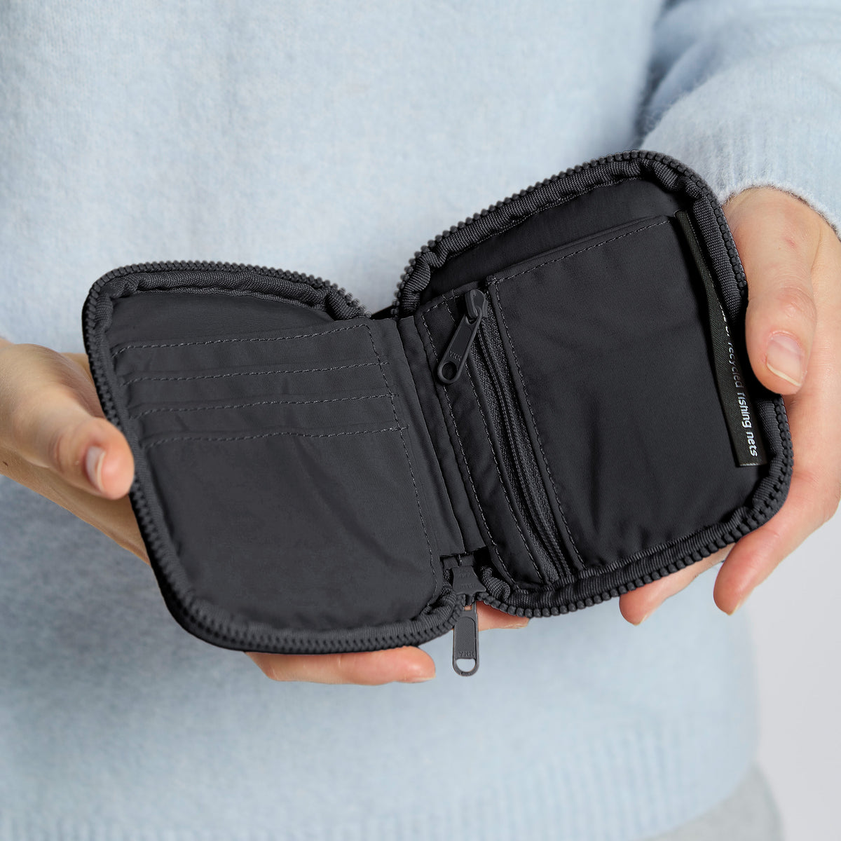 WALLET Accessoire in black (Schwarz) von einer Person in den Händen gehalten.