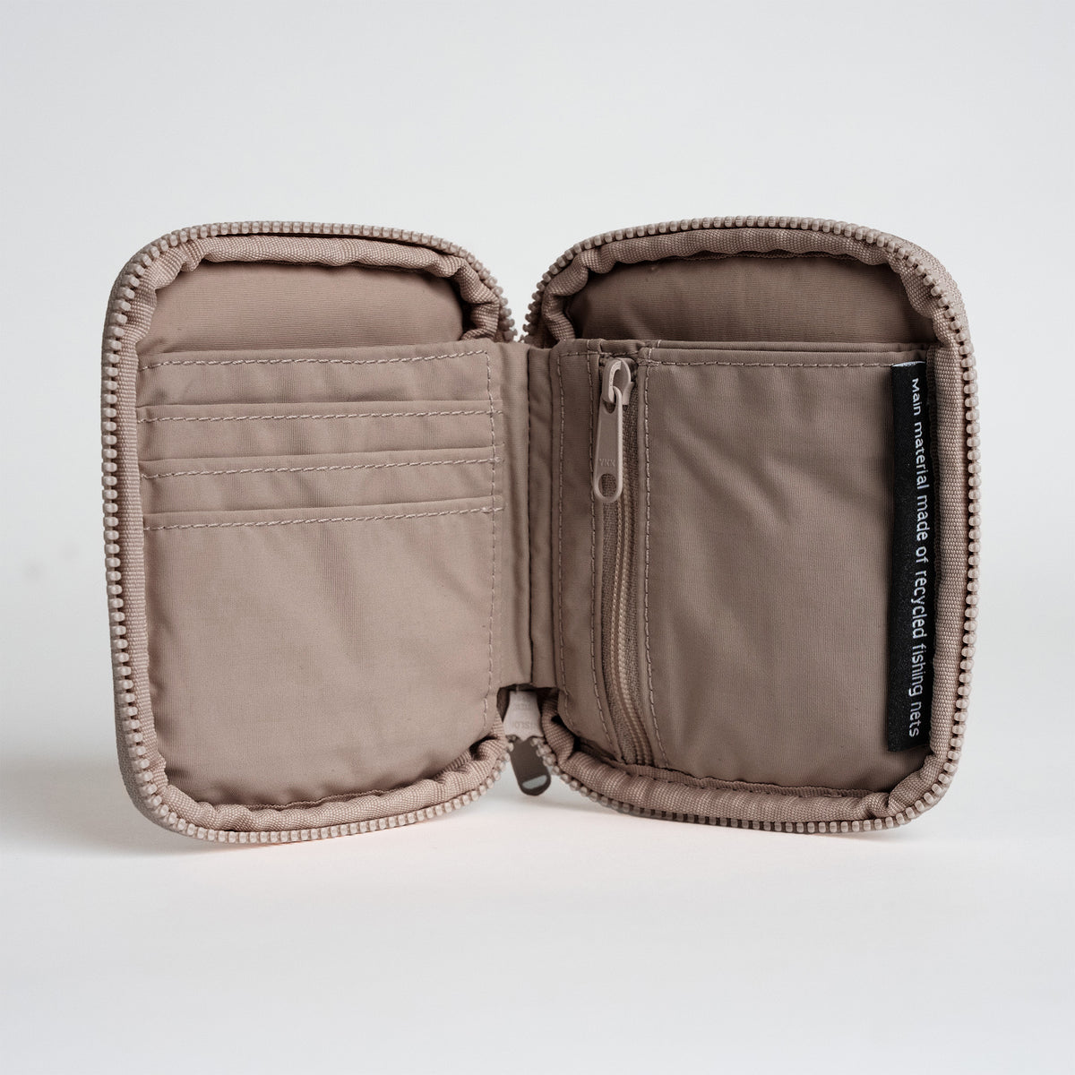 WALLET Accessoires in oyster (klassisches Taupe-Braun), als Studioaufnahme geöffnet. Innenfächer, Reißverschluss und Materialetikett sichtbar.