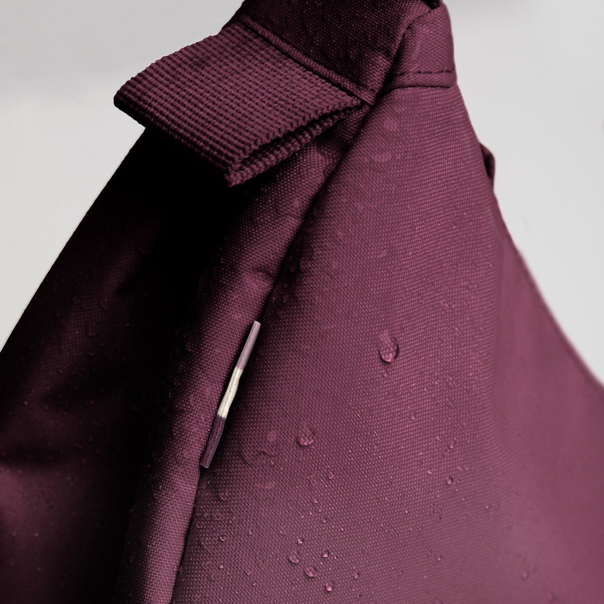 MOON BAG SMALL Tasche in kraken (Weinrot), Detailaufnahme mit Wassertropfen.