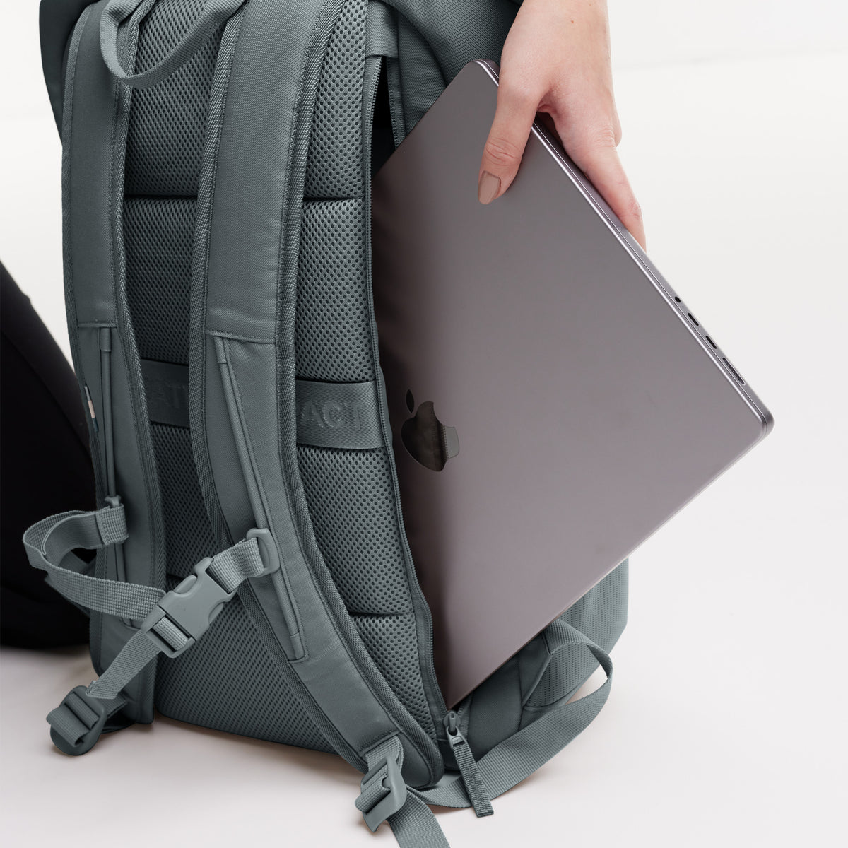 PRO PACK Monochrome Edition Rucksack in basalt (graues Eisblau), eine Frau schiebt einen Laptop in den Rucksack.