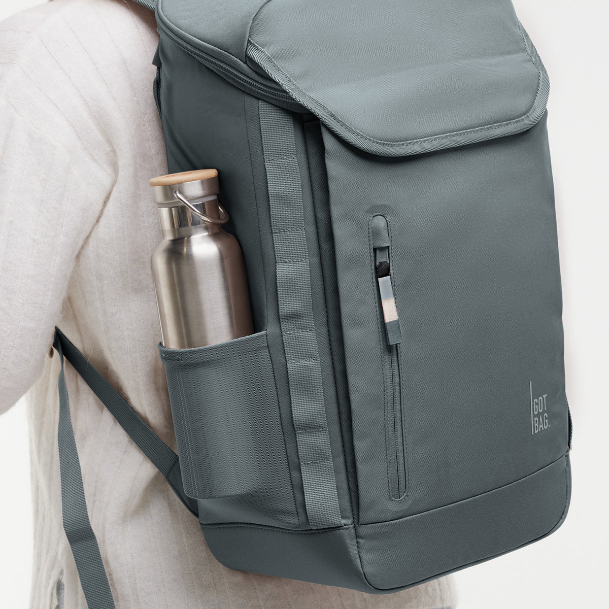 PRO PACK Rucksack in basalt (graues Eisblau) von einer Frau auf dem Rücken getragen, mit Trinkflasche in der Seitentasche.
