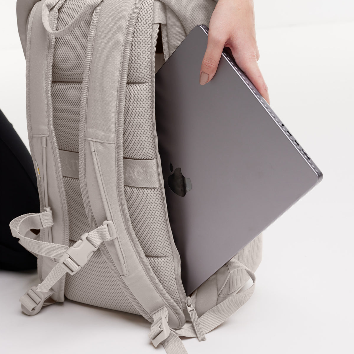 PRO PACK Rucksack in clam (helles, warmes Grau), in den eine Frau einen Laptop steckt.