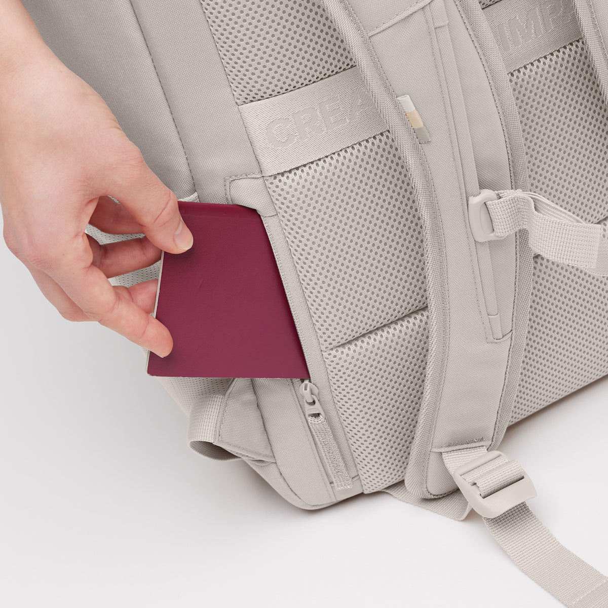 PRO PACK Rucksack in clam (helles, warmes Grau) mit Hand, die einen Reisepass in eine Geheimtasche steckt.