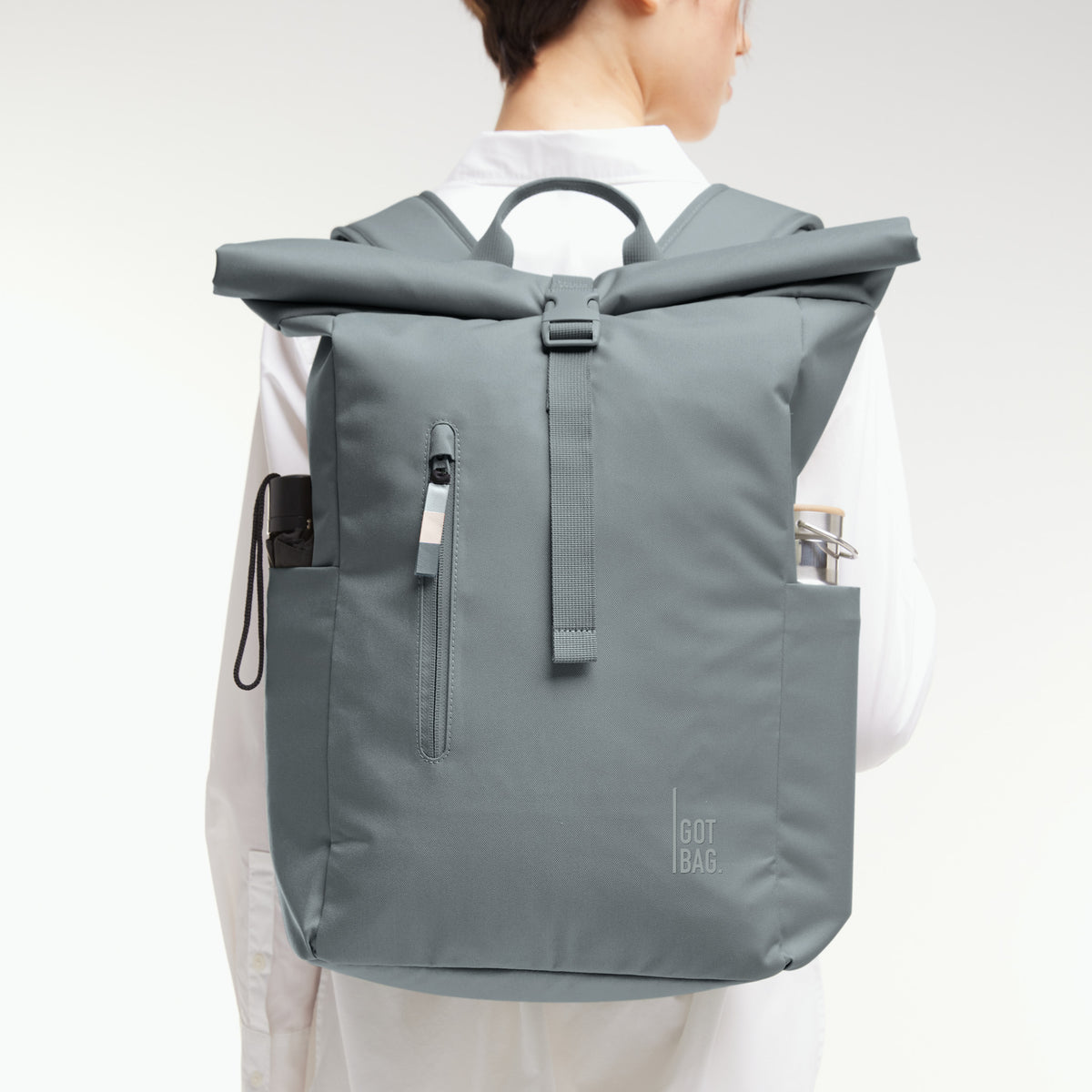 ROLLTOP EASY Rucksack in basalt (graues Eisblau) von einer Frau als Rucksack auf dem Rücken getragen.